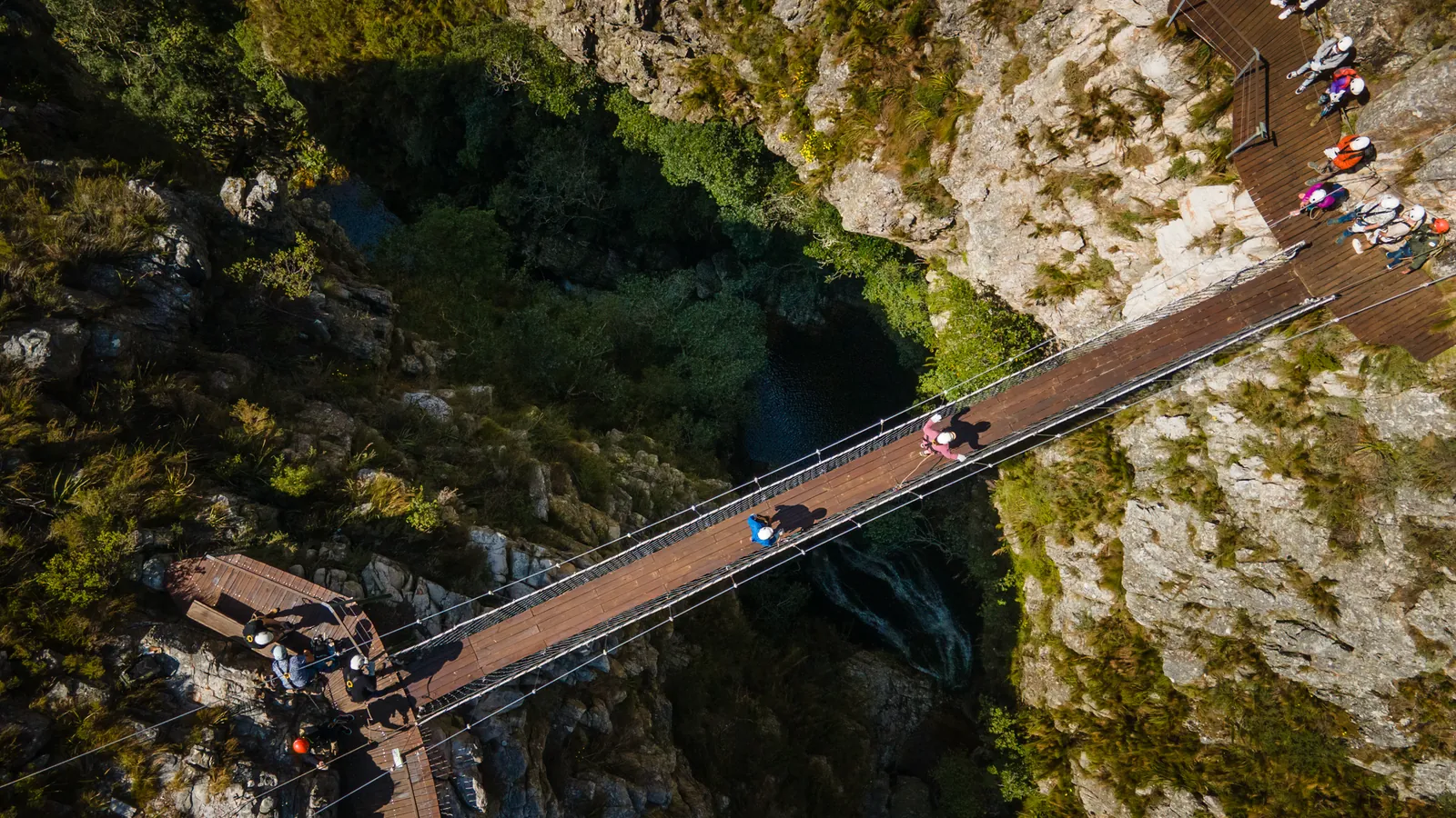 Guests crossing the suspension bridge high above the gorge and the double waterfall in the Hottentots Holland Nature Reserve
